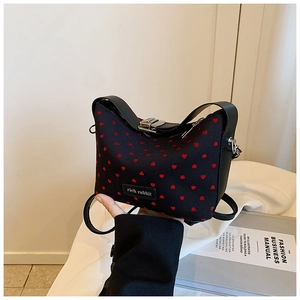 Détail du petit sac noir à motifs de cœurs rouges avec bandoulière et fermoir argenté
