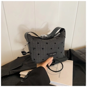 Détail du sac à chevrons gris avec pois noirs et broderie élégante de nœuds papillons