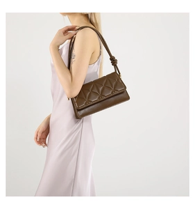 Detail of deep brown quilted shoulder bag featuring decorative strap knots and smooth flap