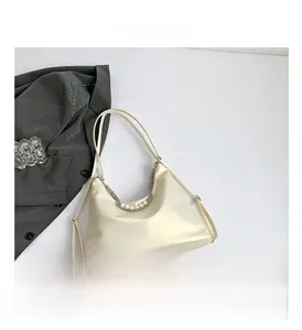 Detail view of off-white faux leather tote bag with elegant pearl and metal chain decoration