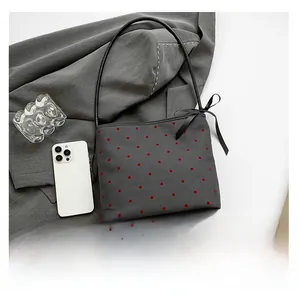 Dettaglio della borsa a spalla grigio scuro a pois con fiocco nero e tracolla in pelle