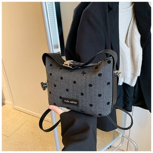 Gros plan sur un sac bandoulière gris à chevrons avec broderie de nœuds noirs