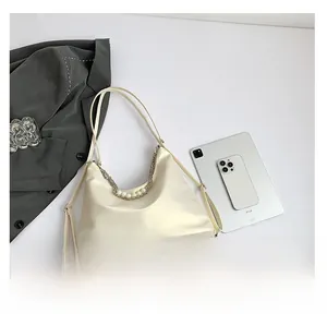 Detail of cream white tote bag featuring decorative pearl and metal chain handle accents