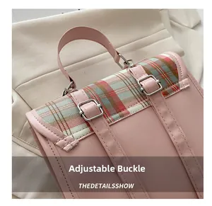 Detail van de verstelbare metalen gespen en roze bandjes op de geruite rugzak