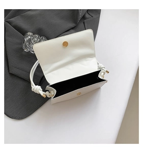 Detail of white minimalist shoulder bag with gold magnetic clasp and black lining