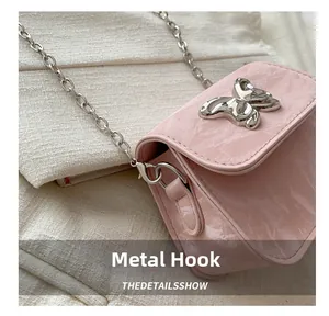 Gros plan du crochet en métal argenté et de la chaîne sur le sac rose en cuir verni