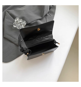 Detailed interior view of a black rectangle shoulder bag with gold magnetic buckle