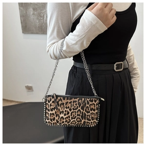 Détail du sac à bandoulière léopard avec clous argentés et chaîne porté par un mannequin
