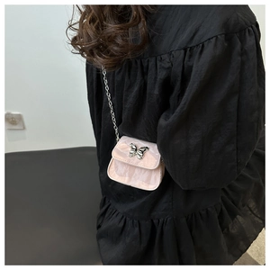 Gros plan sur le mini sac rose marbré avec fermoir papillon argenté et bandoulière