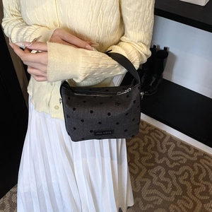 Sac à main à pois avec étiquette rich rabbit porté par un mannequin en jupe et cardigan