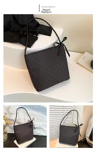 Dettaglio della borsa a spalla con motivo a cuori rossi e fiocco decorativo nero