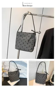 Dettaglio borsa a mano grigia a pois con ricamo a fiocco nero e tracolla sottile elegante