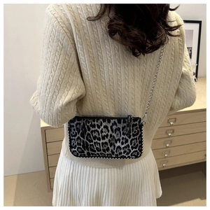 Détail d'un mini sac à chaîne à motif léopard avec clous argentés sur un modèle