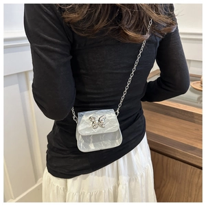 Vue arrière d'un mannequin portant le mini sac carré argenté avec chaîne papillon et texture métal