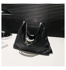 Detailed close-up of a black tote bag with elegant large pearl and metal chain accents