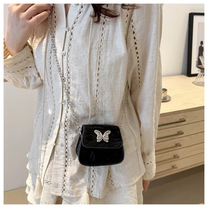 Gros plan sur un mini sac en velours noir avec boucle papillon argentée et fine chaîne