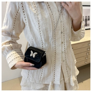 Mini sac bandoulière noir avec papillon argenté et bandoulière chaîne sur modèle