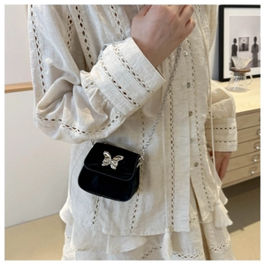 Gros plan d'un mini sac bandoulière noir avec bijou papillon sur un mannequin