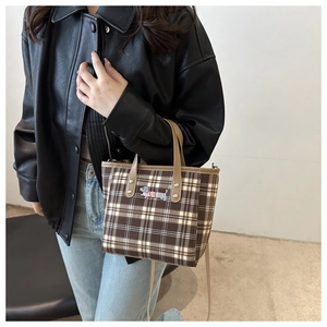 Detail der karierten Beuteltasche mit Dackel-Aufnäher an Model mit Lederjacke präsentiert