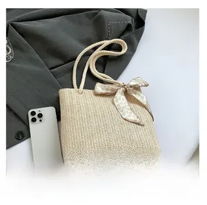 Détail du sac cabas en paille tressée avec un foulard décoratif à motif de petits cœurs