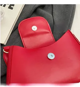 Détail du sac en cuir rouge montrant le fermoir magnétique argenté et la doublure