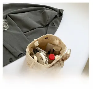 Détail de l'intérieur du grand sac cabas en paille montrant les articles du quotidien
