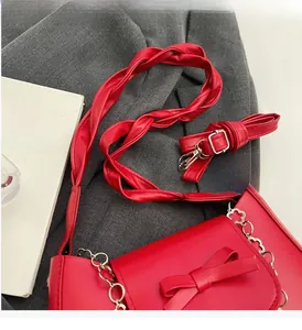 Détail du sac à chaîne rouge montrant le nœud décoratif et la poignée tressée argentée