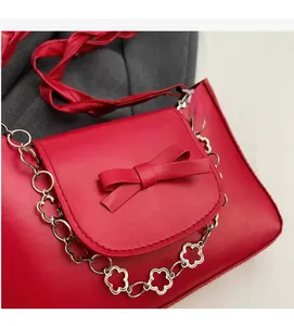 Détail du sac à bandoulière en cuir rouge avec nœud et chaîne à fleurs argentées