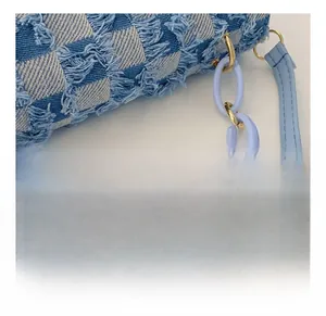 Detail of blue denim checkered fabric with lavender matte chain and golden hardware