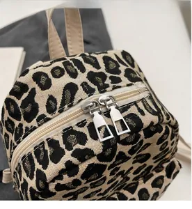 Dettaglio del tessuto jacquard leopardato e delle doppie cerniere in metallo sullo zainetto