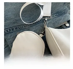 Detail der weißen Canvas-Unterarmtasche mit passender runder Geldbörse auf Jeans