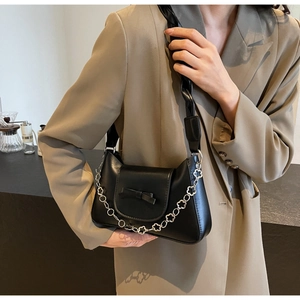 Détail du sac à bandoulière noir avec nœud, chaîne fleurie argentée et large sangle