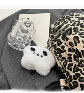 Dettaglio di un ciondolo a nuvola in peluche bianco su uno zaino alla moda