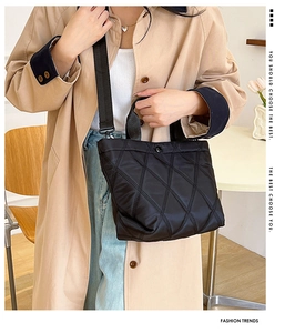 Detail of black quilted bucket bag with rhombus stitching and fabric shoulder strap