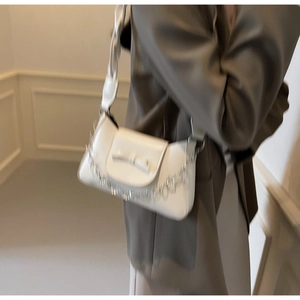 Détail du sac bandoulière blanc avec nœud délicat et bandoulière en cuir tressé
