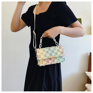 Detail of colorful woven plaid handbag featuring fringe edges and white chain handle