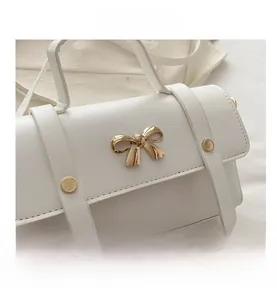 Detail of white PU leather handbag with golden bow metal clasp and rivet accents