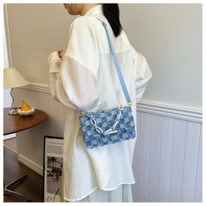 Blue and white checkered denim crossbody bag with fringe trim and a metal chain strap