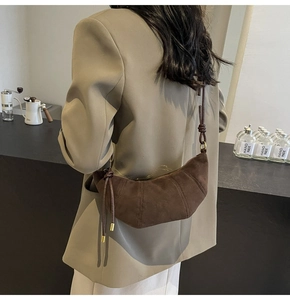 Detail einer braunen Wildleder-Croissant-Tasche mit Knotengurt, von Model getragen