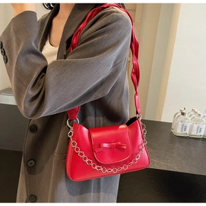 Détail du sac rouge à bandoulière avec nœud décoratif et chaîne en métal argenté
