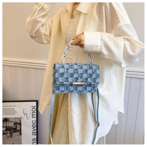 Detail of blue denim checkered bag featuring fringe edges and golden chain strap