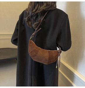 Detailansicht der braunen Wildleder-Hörnchentasche mit feinen Nähten und Metallknoten