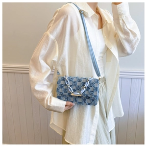 Detail of light blue denim crossbody bag with checkerboard pattern and frayed edges