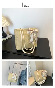 Détail du sac cabas en paille kaki avec texture tissée et foulard en soie à motif cœur