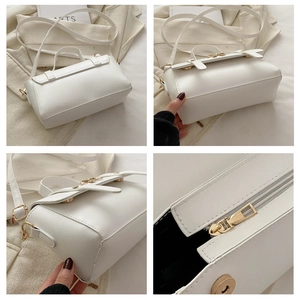 Detail view of white PU leather handbag featuring zipper closure and magnetic metal buckle