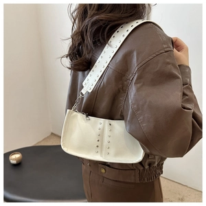 Détail du sac à main blanc en cuir grainé avec rivets métalliques et fermeture éclair