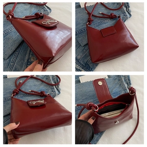 Detail view of burgundy leather shoulder bag with silver bow accent and interior pocket