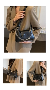Détail du sac noir avec chaîne à fleurs argentées et nœud élégant sur le cuir