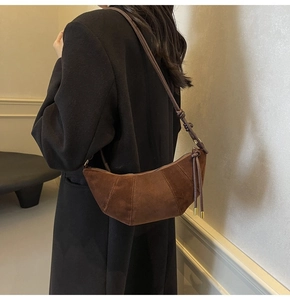 Detailaufnahme der braunen Wildleder-Halbmondtasche mit Nähten und Goldverzierungen