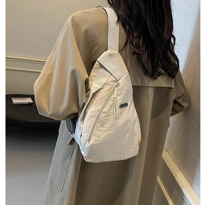 Vue détaillée du sac de poitrine léger en nylon beige porté montrant la coupe et la texture
